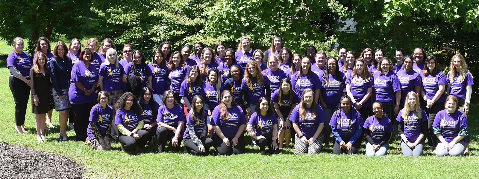 图为一大群波胆网站的学生穿着紫色的新领导力项目t恤, 一起在外面的草地上摆姿势. 